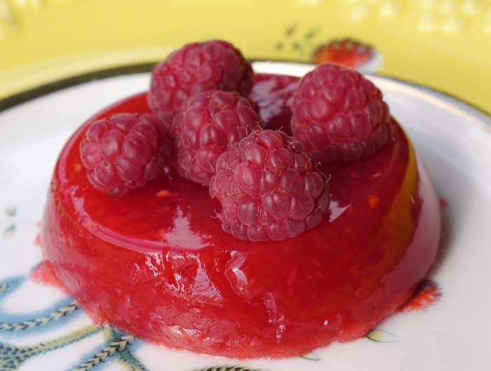 Вийняти форми з ягідним желе з холодильника, опустити в в теплу воду, акуратно викласти малинове желе на десертні тарілки, прикрасити на свій смак ягодами малини